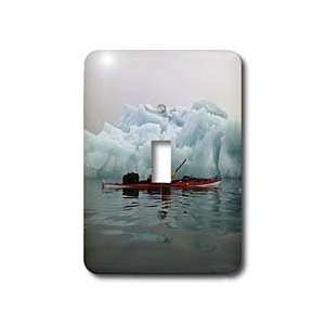 young man paddling past an iceberg in Forlandssundet, Svalbard, Norway 