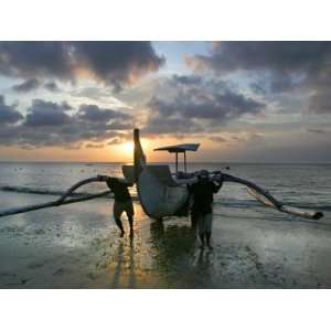  Balinese Fishermen Push Their Boat to Land During Sunset at a Beach 